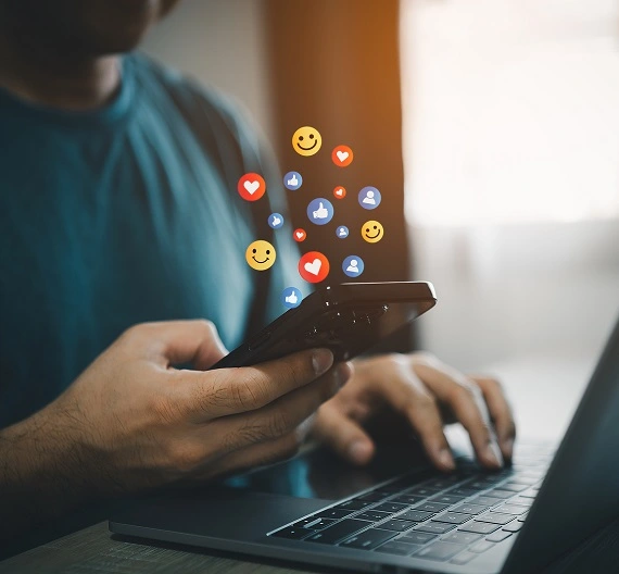 homem mexendo no celular com vários icónes de redes sociais saindo da tela