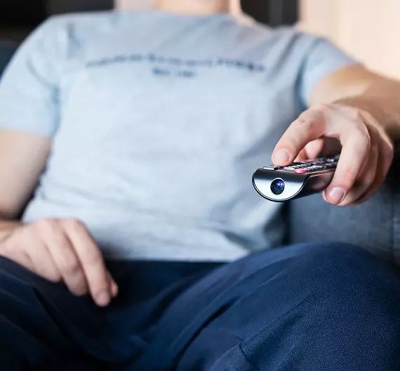 homem sentado no sofá assistindo streamings